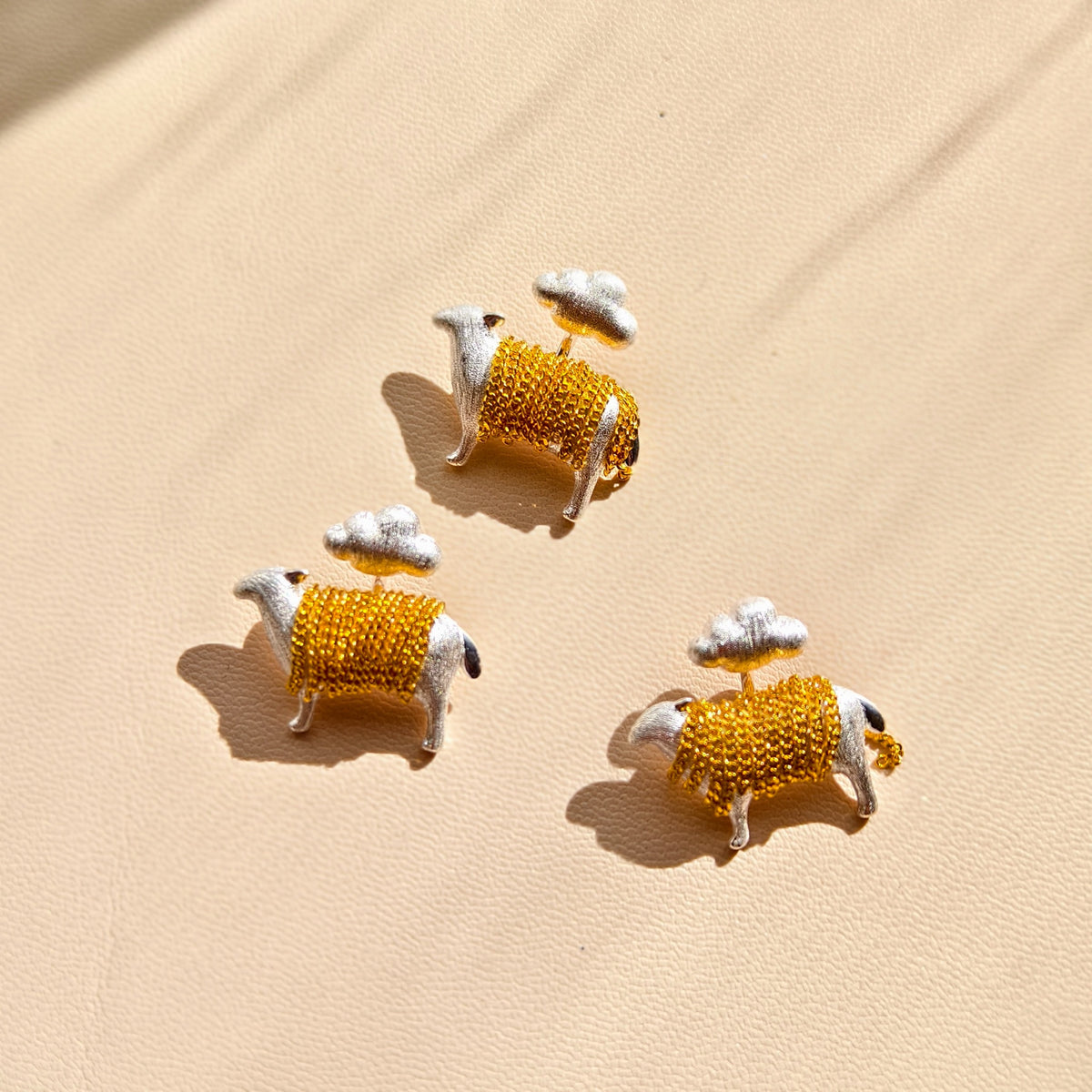 Three cloud and lamb pendants displayed together; sold individually