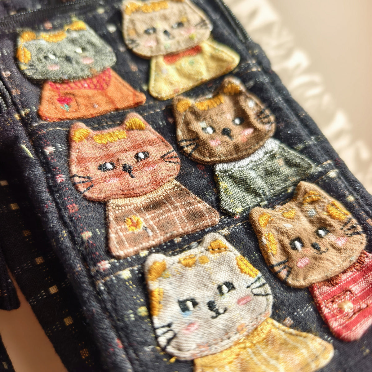 Close-up of the navy bag's cat appliqués and embroidered details