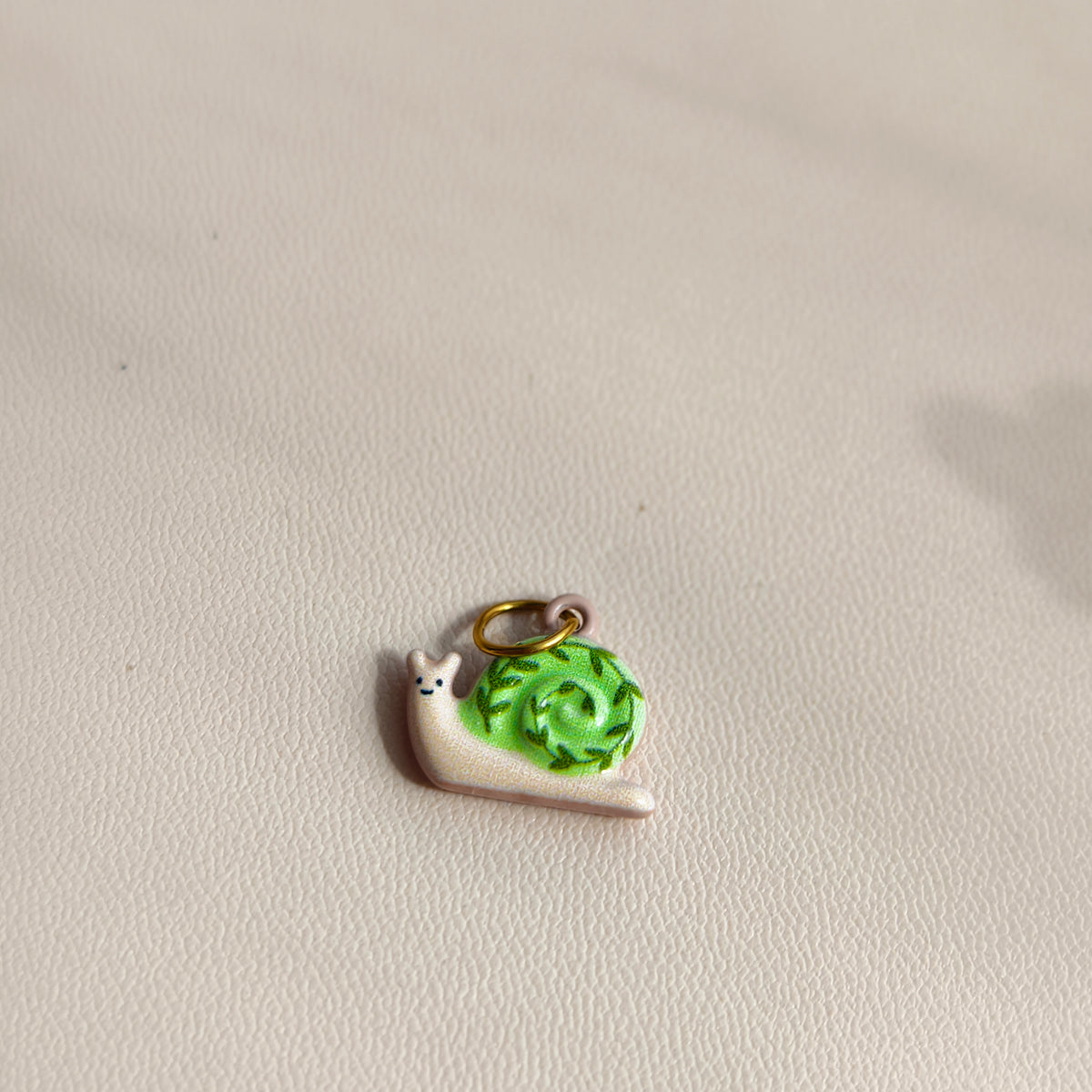 Actual Ivy Trail Snail stainless steel charm with a cream body, green spiral shell and gold-tone ring